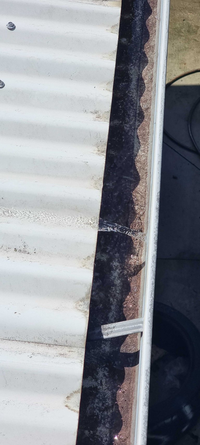 Close-up of weathered RV or trailer exterior showing white corrugated siding with visible rust stains and dark weathering along the edge trim